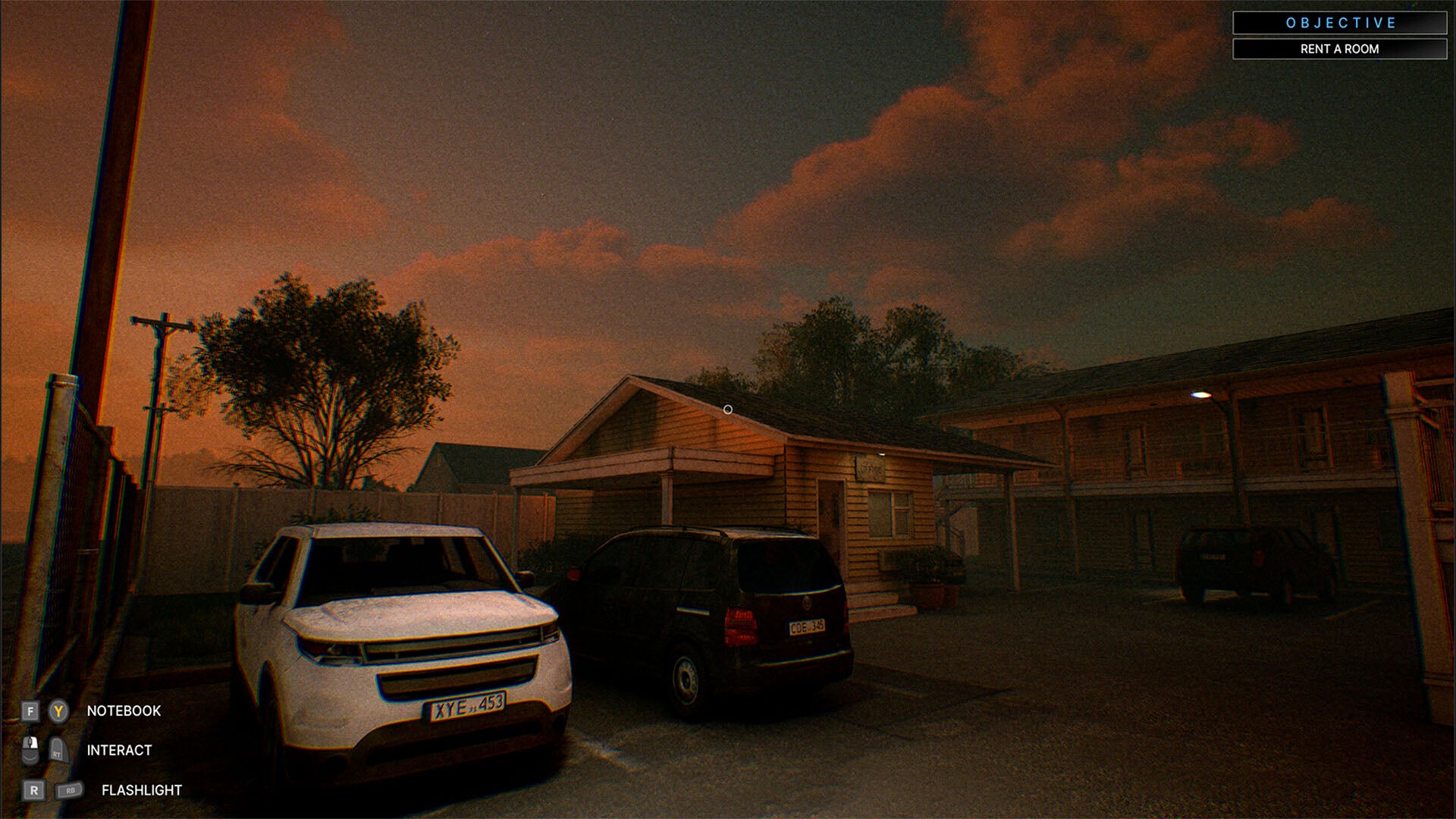 Two cars parked outside a motel with a sunset sky.