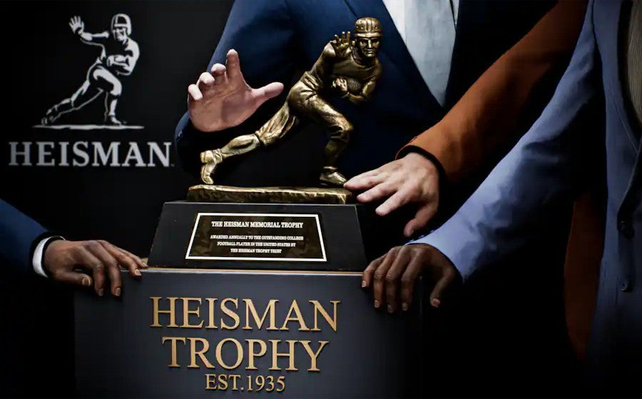 Heisman Trophy being held by a person with the Heisman logo in the background