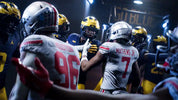 Football players in a huddle with 'Go Blue' banner in the background
