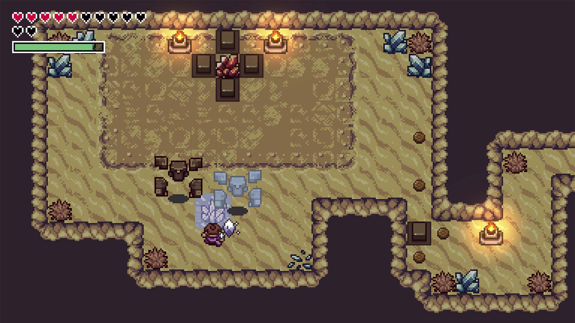 Pixel art screenshot of a top-down fantasy dungeon scene with a small character near stone blocks, torches, chests, and a map-like border on a dark background.