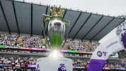 Silver trophy with a green center and crown on top, set against a stadium background.