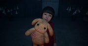 Child holding a plush toy in a dark room with hanging decorations