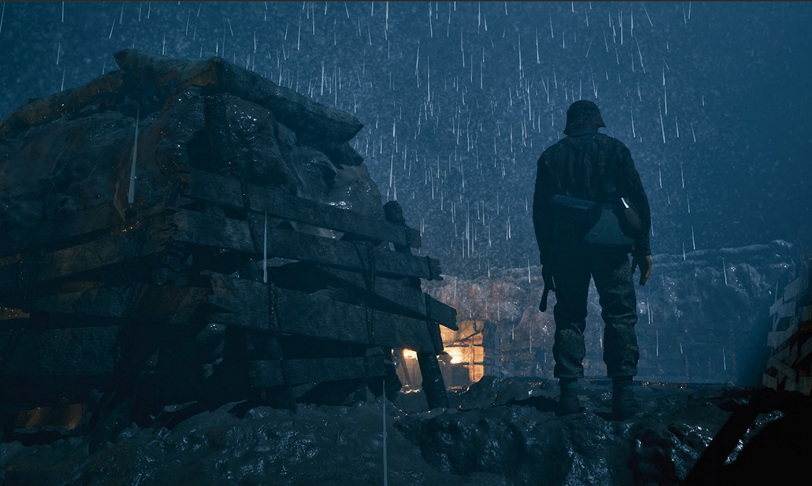 Person standing in front of a small wooden cabin in the rain at night.