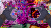 A highly detailed, vibrant fantasy board game scene viewed from a first-person perspective, featuring two large gray hands reaching toward a central grid of colorful game tiles surrounded by glowing magenta energy rings.