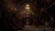 Dark, ornate interior with a grand staircase and chandelier