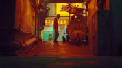 Person standing in a dimly lit alleyway with a vehicle and various objects around